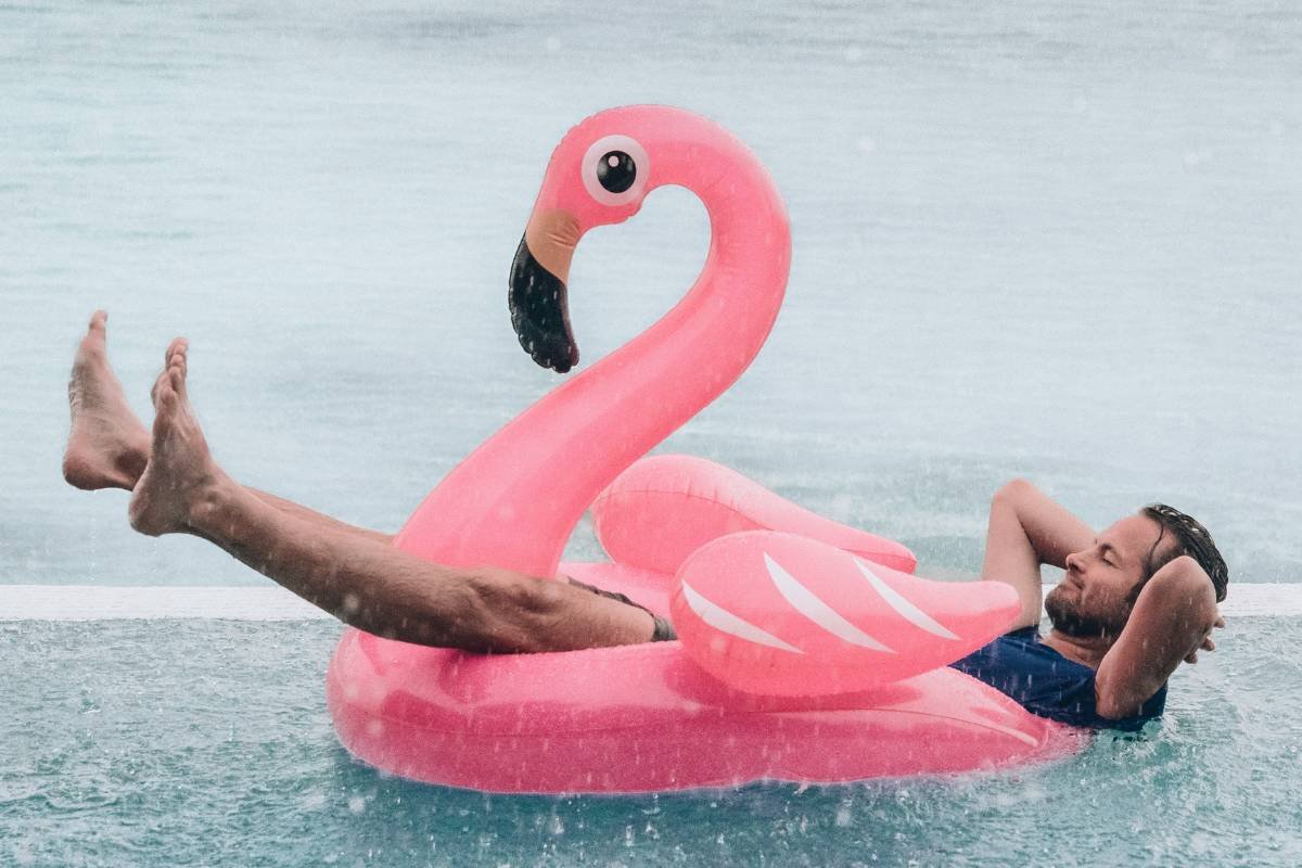 Man on a pink flamingo float in Algarve rain – Amo-te Olhão Man relaxing on a pink flamingo float under the rain in Algarve — a fun photo for the guide Things to do in Algarve when it rains.